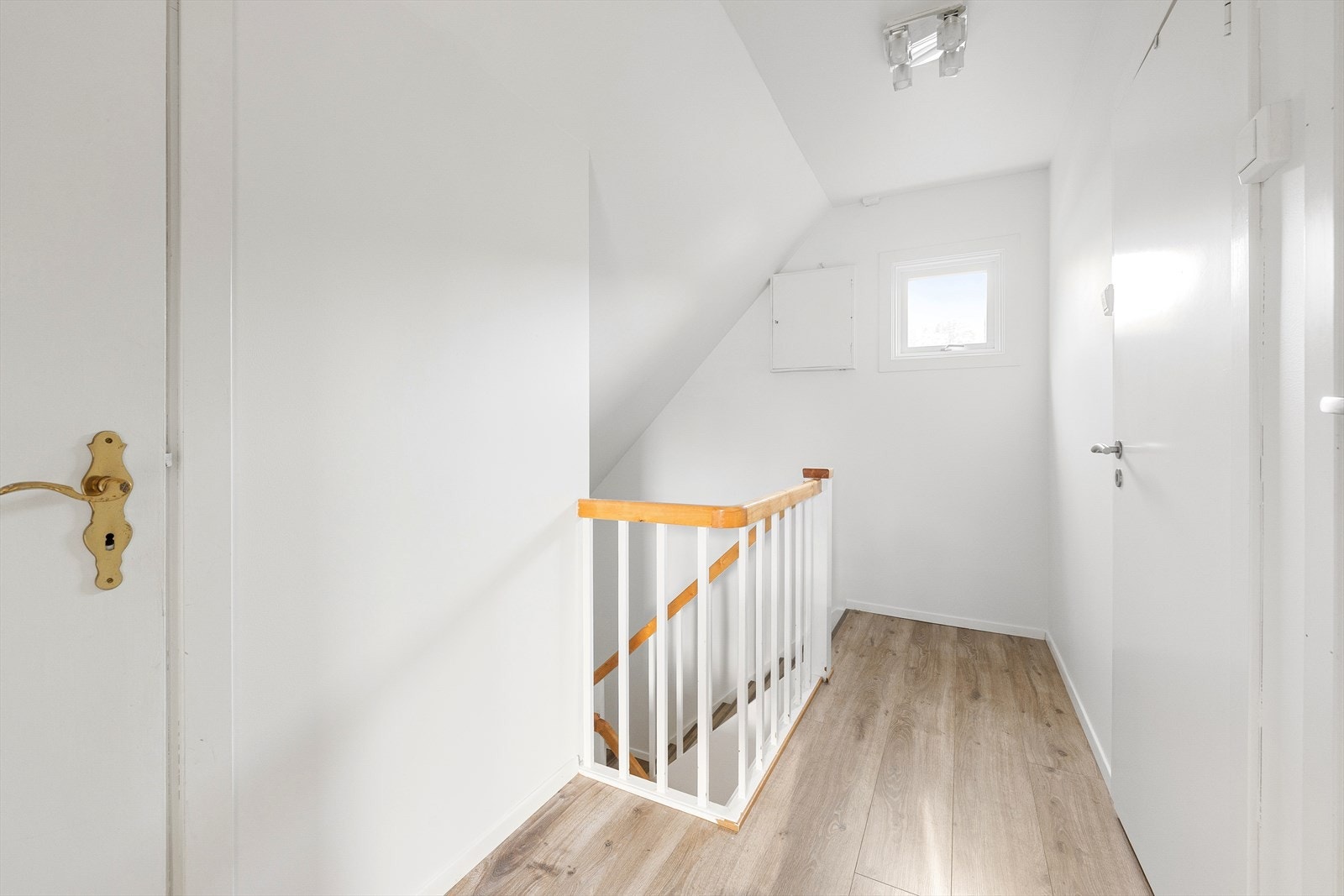 Laminatgulv og malt rekkverk gir en lys og funksjonell trappegang. Det er plass til mindre oppbevaringsløsninger under skråtaket. Galleribilde