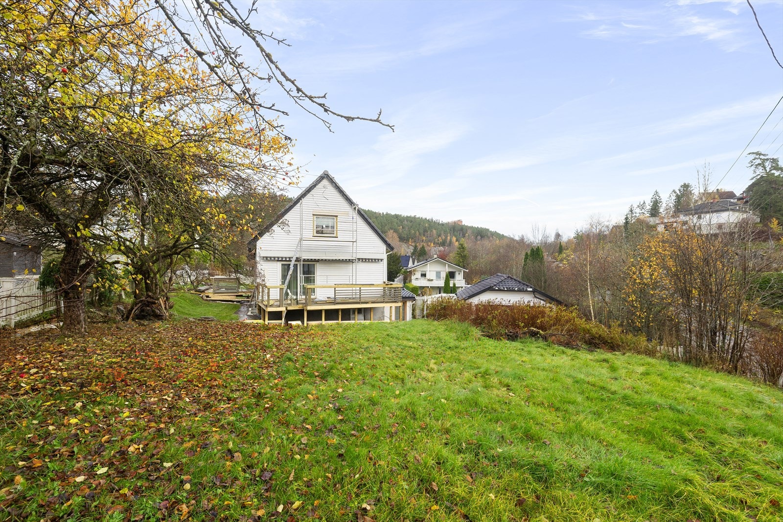 Boligen har en terrasse med adkomst fra stue, og tomten er omgitt av frodig vegetasjon og en paviljong med terrassebord. Galleribilde