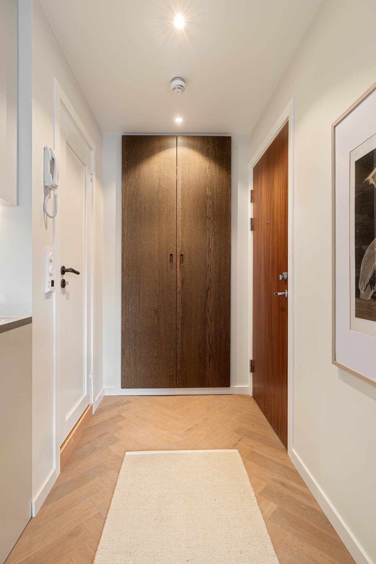 Spesialtilpasset garderobe i entré med doble dører/fronter i mørk eikefinér - matchende baderom. Galleribilde