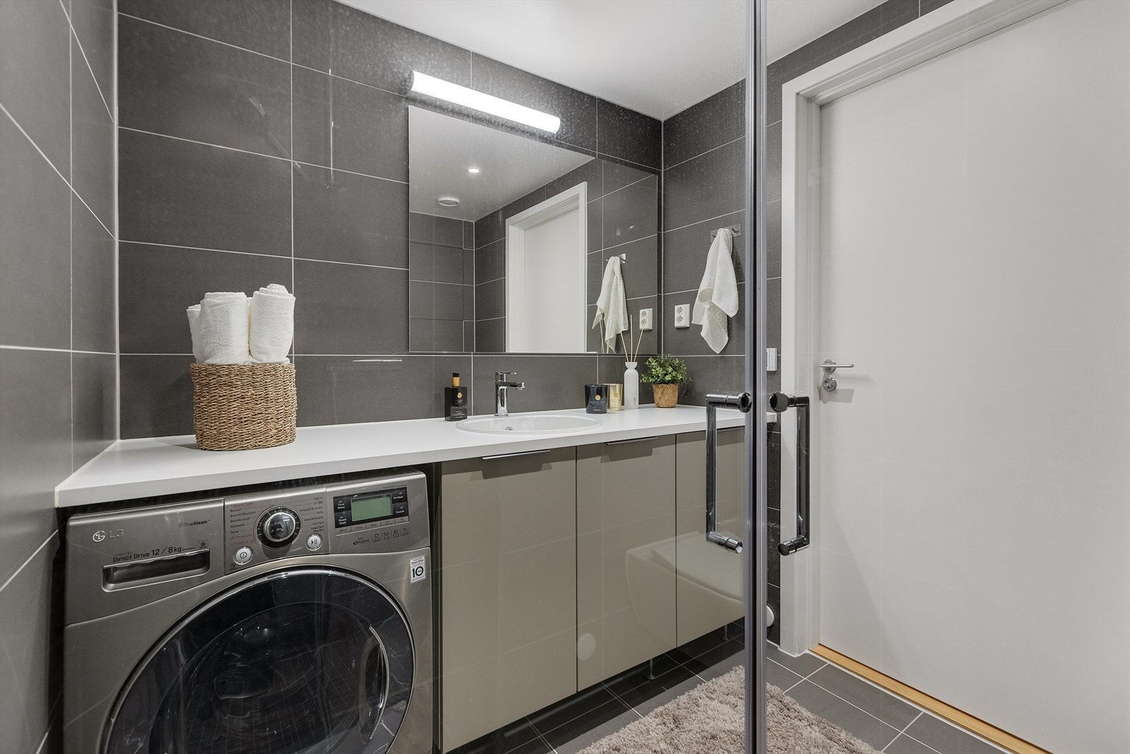 Innredningen har servant på underskap, vegghengt klosett, speil, dusjnisje med svingbare glassdører og opplegg for vaskemaskin. Galleribilde