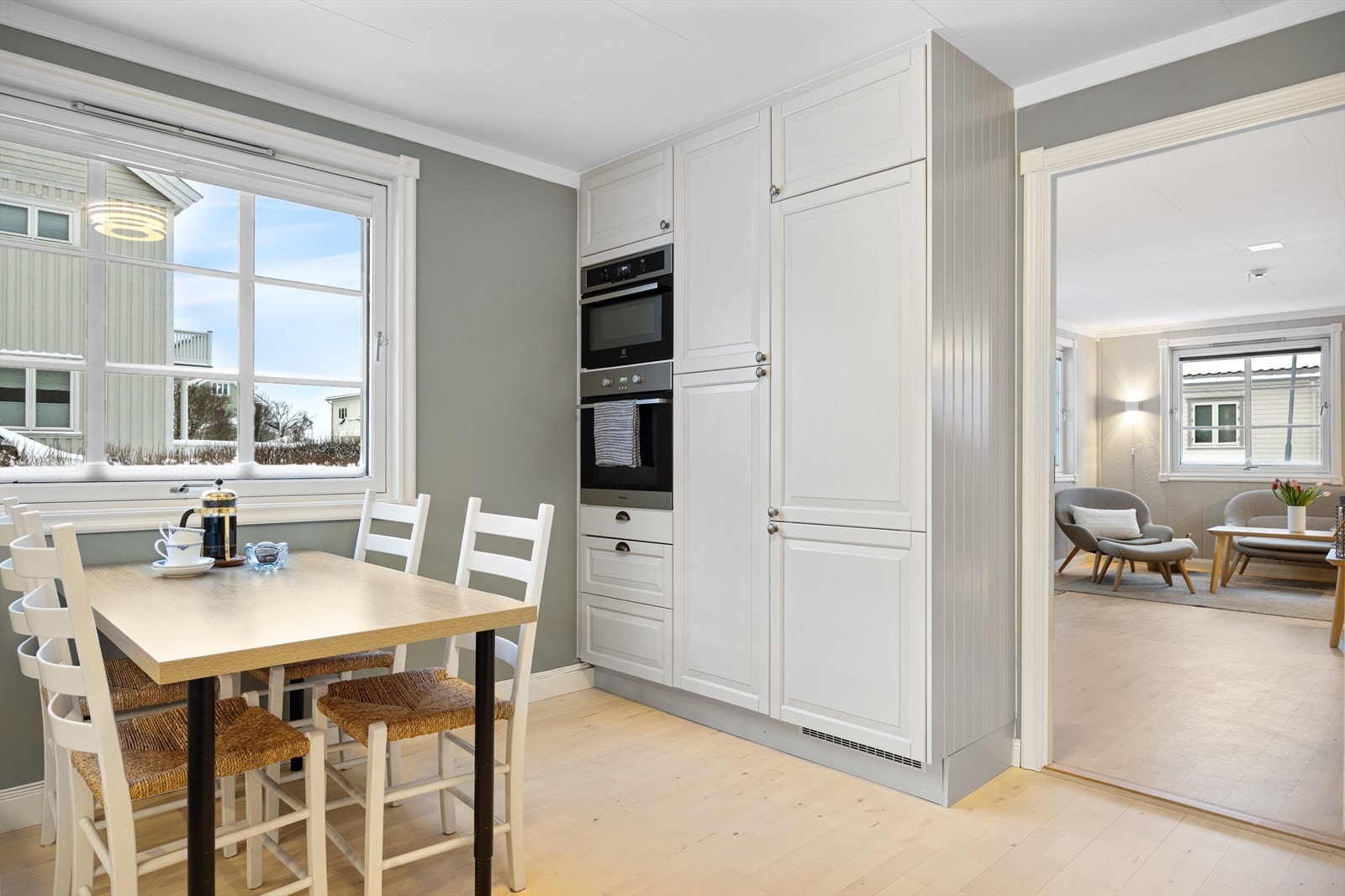 Kjøkkenet i 1. etasje fremstår som lyst og innbydende, med en pen innredning med profilerte fronter og takhøye skap som gir rikelig med oppbevaringsplass. Galleribilde