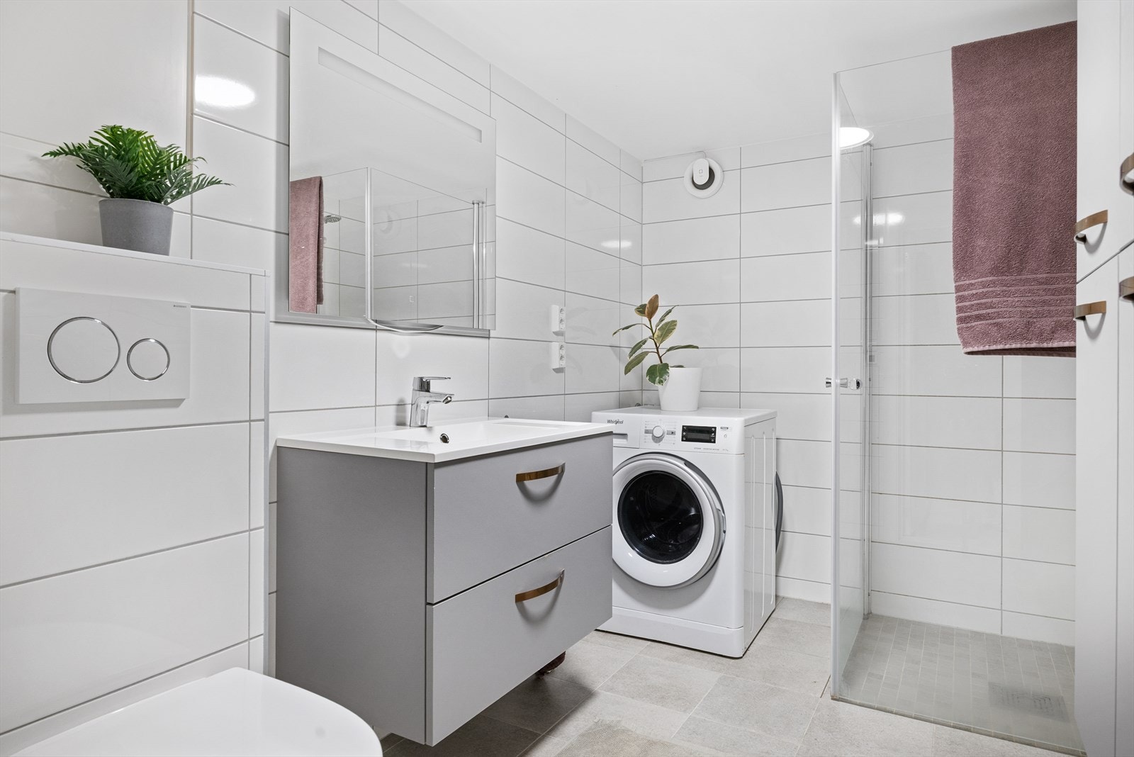 Bad i kjeller fra 2022. Rommet har flislagte gulv og vegger, servantskap, klosett med innebygd sisterne og innfellbare dusjvegger for god plassutnyttelse. Opplegg for vaskemaskin og mekanisk avtrekk sikrer komfort og god ventilasjon. Galleribilde