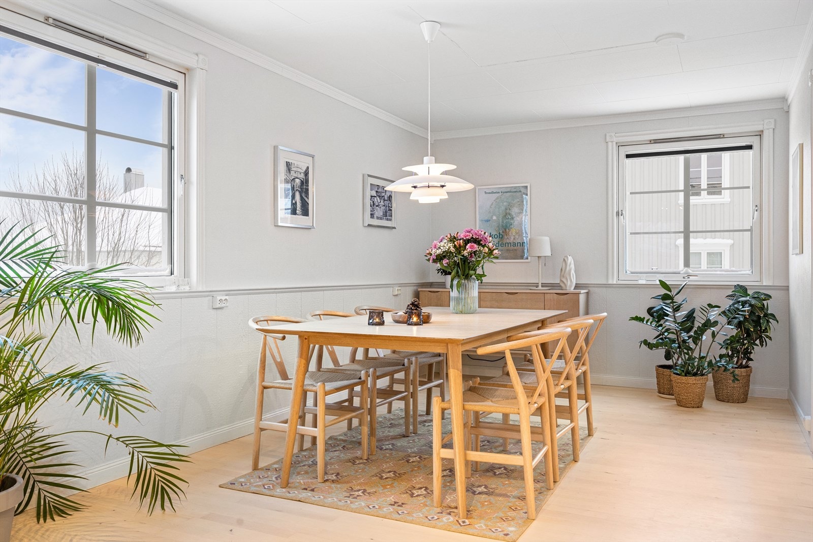 Den åpne løsningen mot stue skaper en luftig og sosial atmosfære, og store vindusflater slipper inn naturlig lys som gir en varm og innbydende stemning. Galleribilde