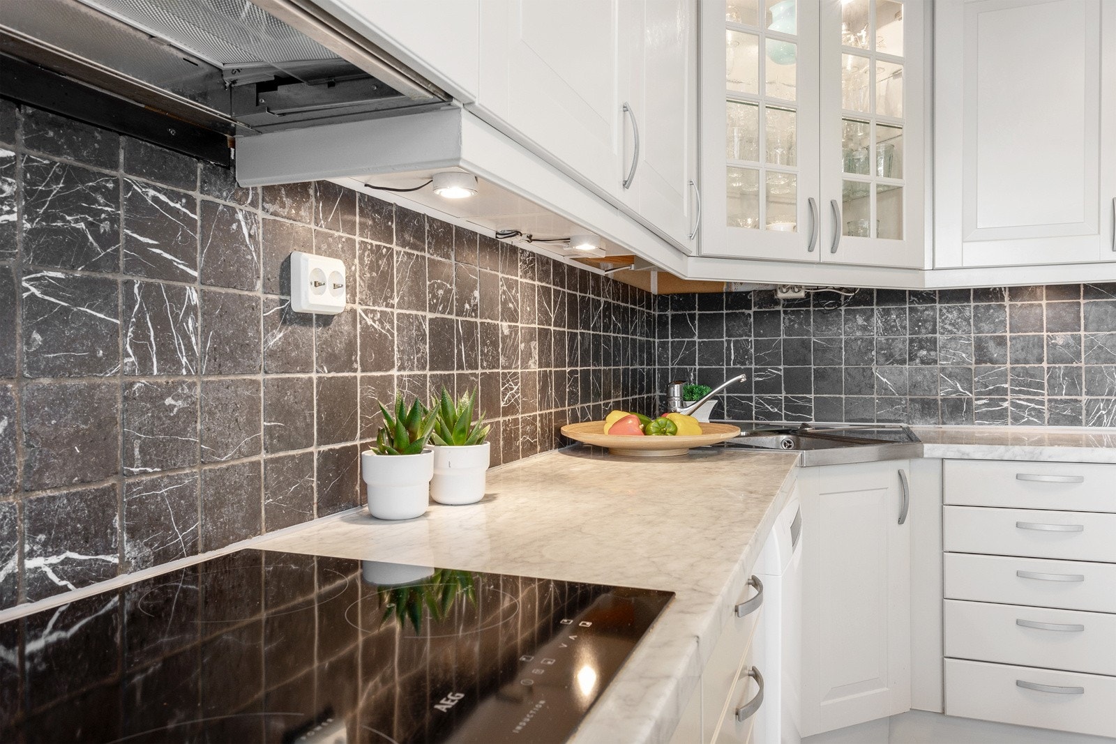 Skap og skuffer har kremfargede rammefronter, enkelte har vitrinedører og benkeplatene er i granitt. Galleribilde