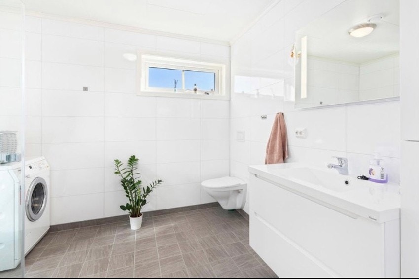 Flott bad med flislagt gulv, flismønstrede plater på veggene, speilskap og stor innredning med ekstra høyskap. Galleribilde