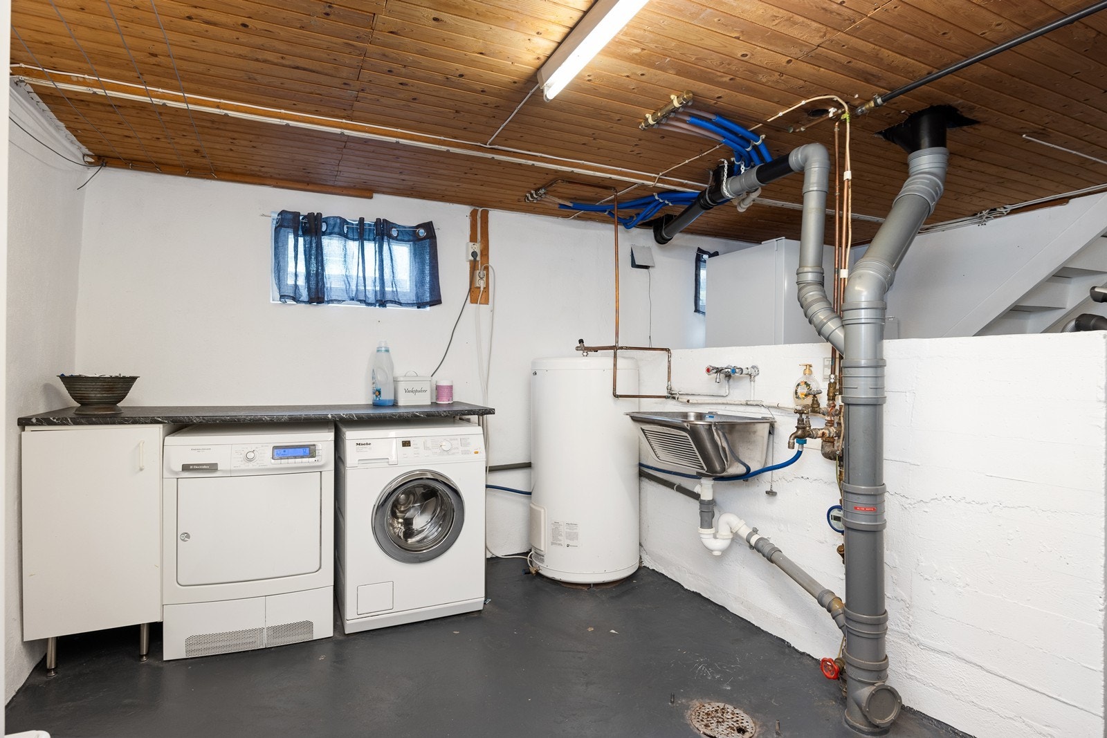 Praktisk vaskerom i kjeller med benkeplass og utslagsvask. Galleribilde