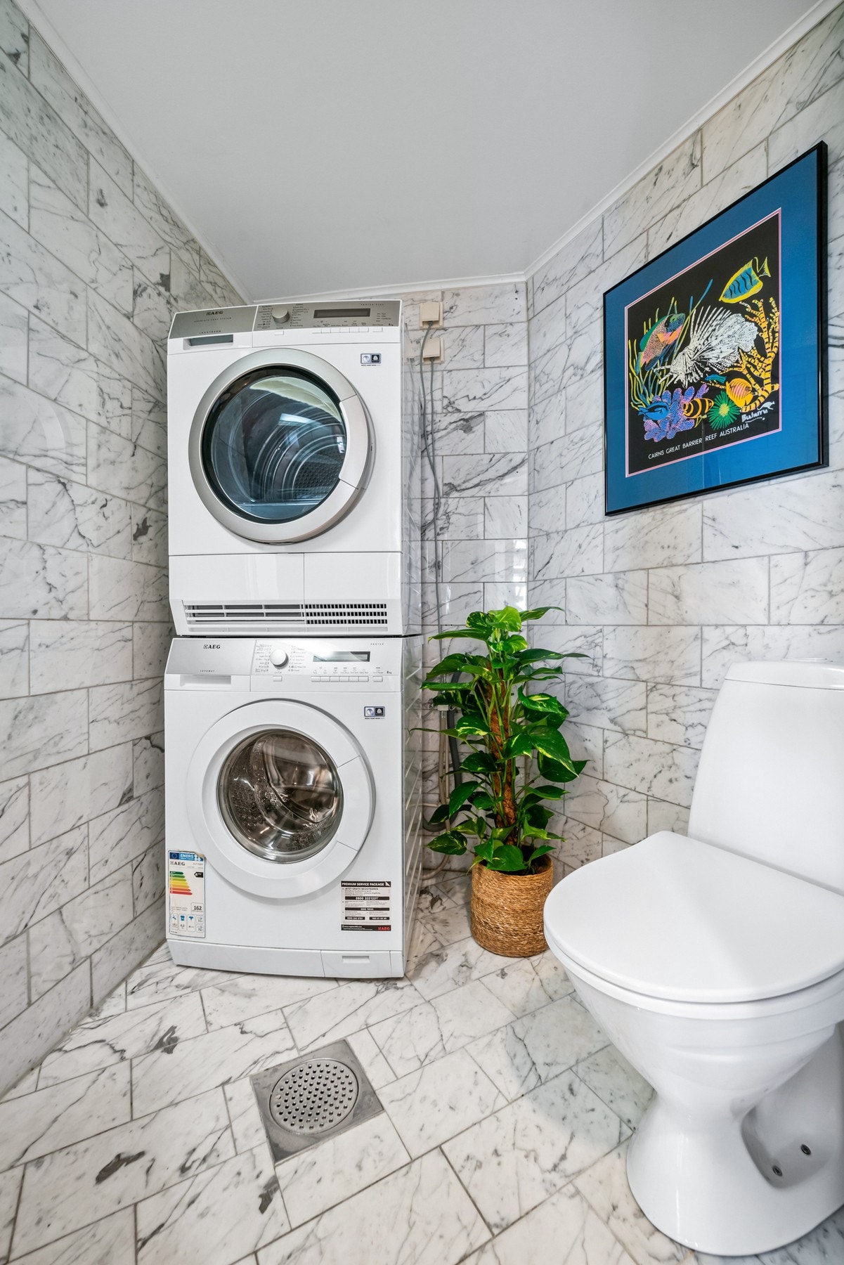 Separat vaskerom/toalettrom med fliser på gulv og vegger. Praktisk innredet med servant, gulvstående toalett og opplegg for vaskemaskin. Galleribilde