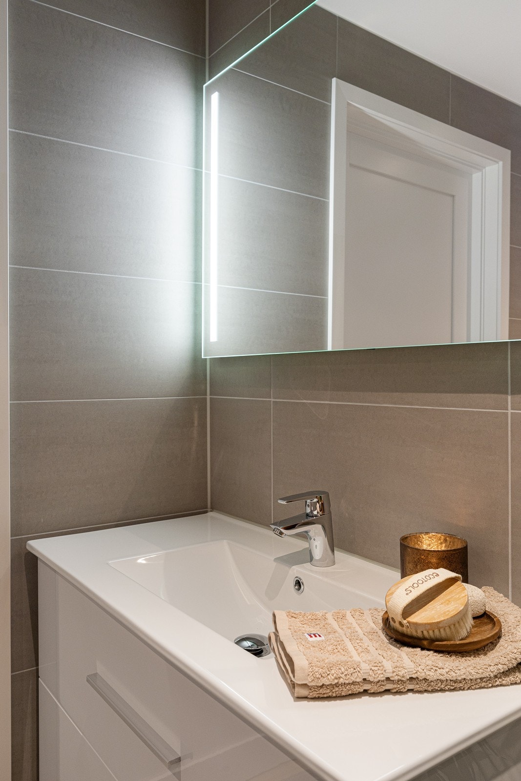 Den hvite baderomsinnredningen har skuffseksjon og speil med belysning. Galleribilde