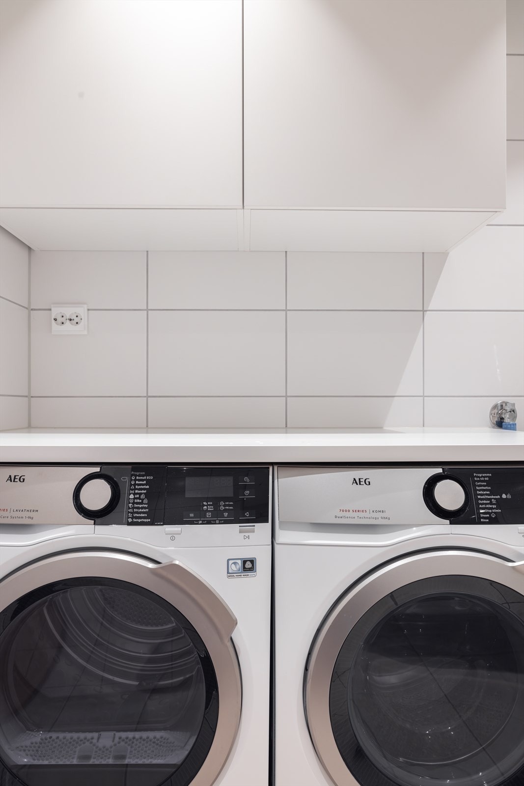 Her er det opplegg for vaskemaskin og tørketrommel under en praktisk arbeidsbenk, samt veggskap. Galleribilde