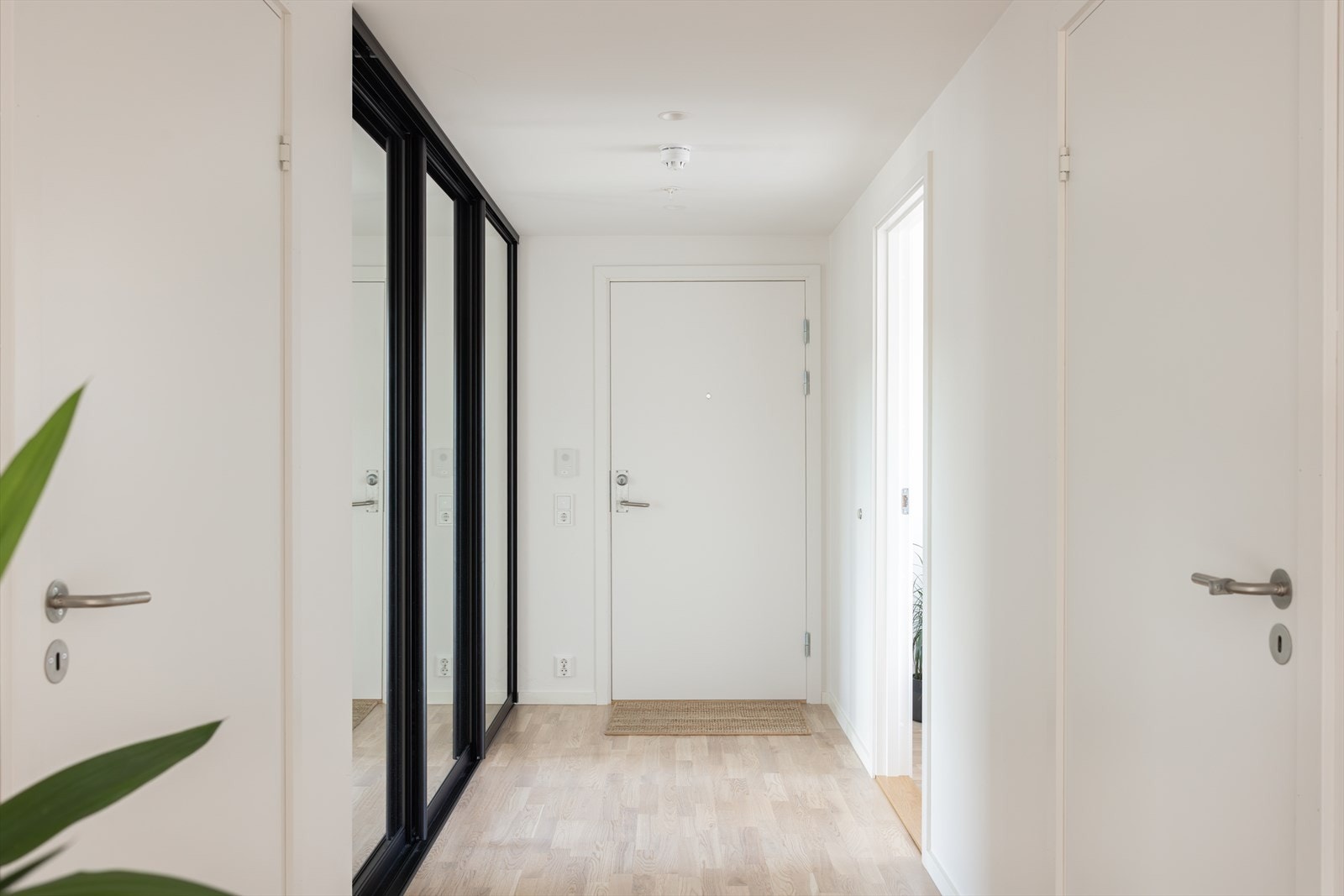 Entreen er innbydende og smart innredet med en stor skyvedørsgarderobe, som har elegant, sort ramme og speilfronter for en forstørrende effekt. Galleribilde