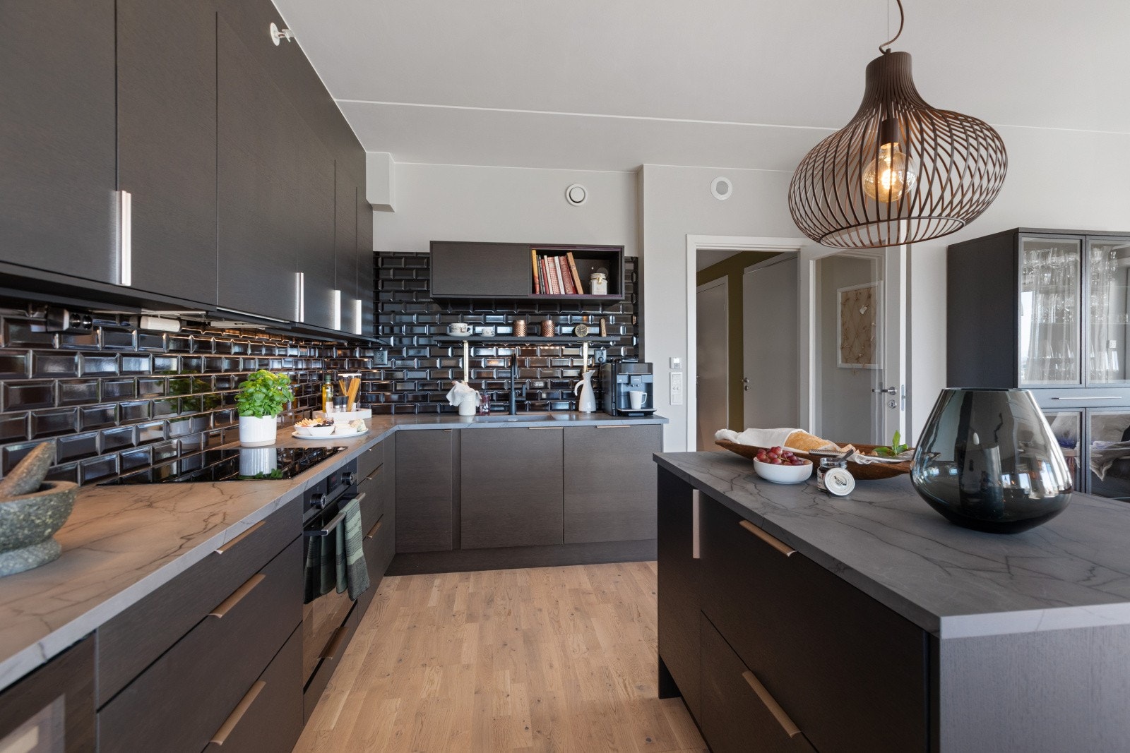 Påkostet kjøkken med ekstra kjøkkenøy og fliser mellom overskap- og benkeplate. Galleribilde