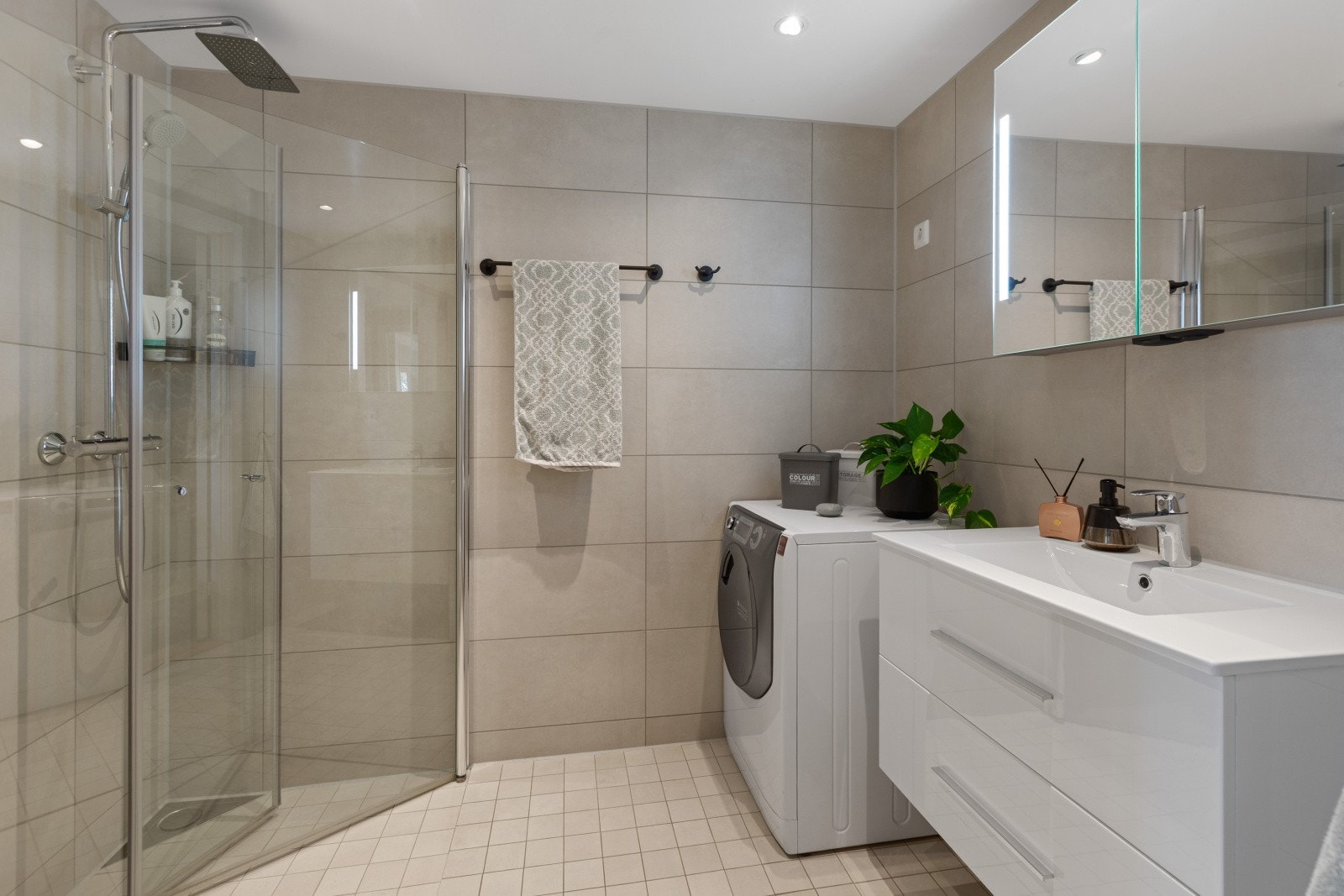 Pent flislagt baderom med varme i gulv. Badet er innredet med servantinnredning, dusj med innfellbare glassdører og toalett. Videre er det opplegg for vaskemaskin og tørketrommel i søyle. Galleribilde