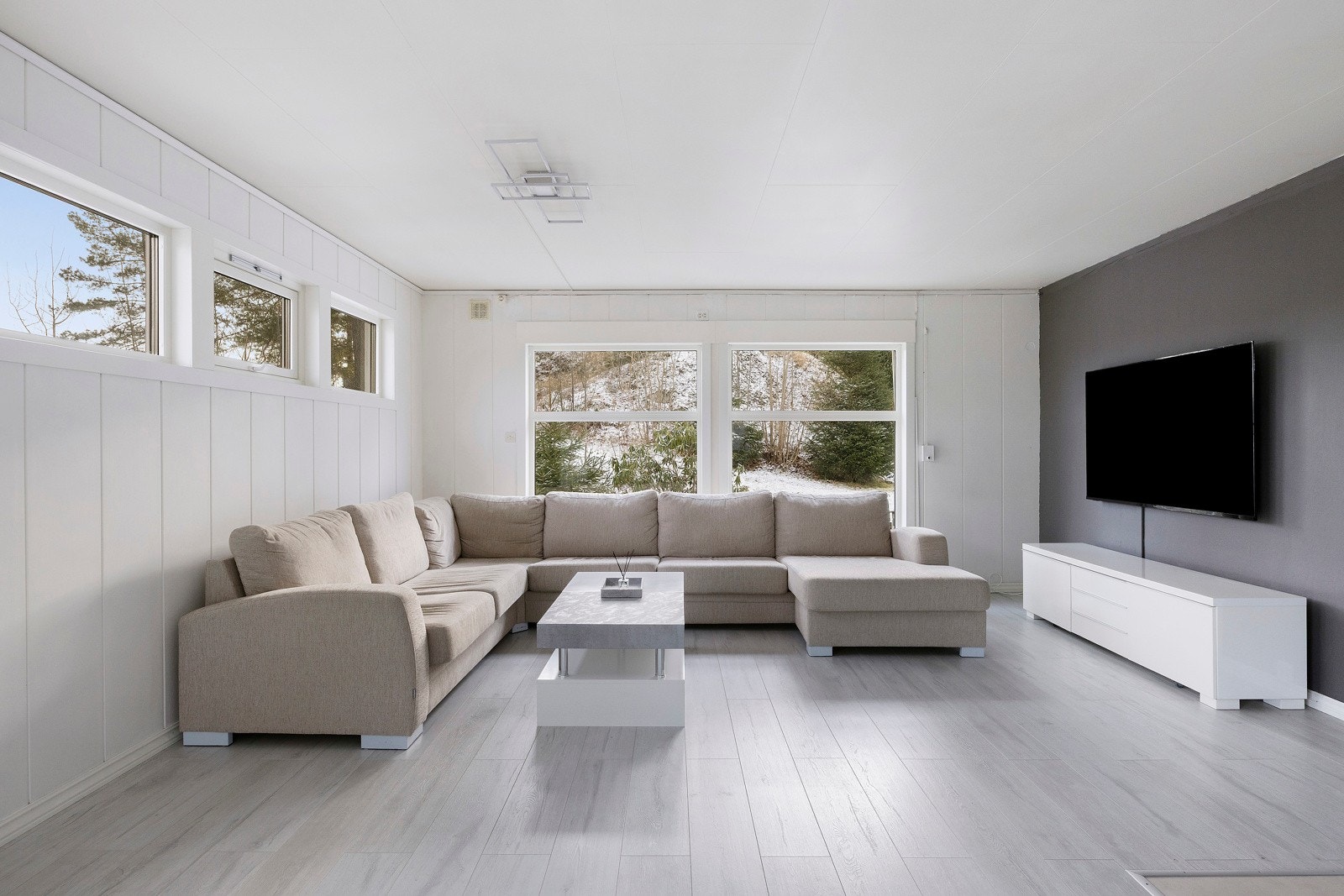 Lys og romsli stue og spisestue med vinduer på flere sider. Galleribilde