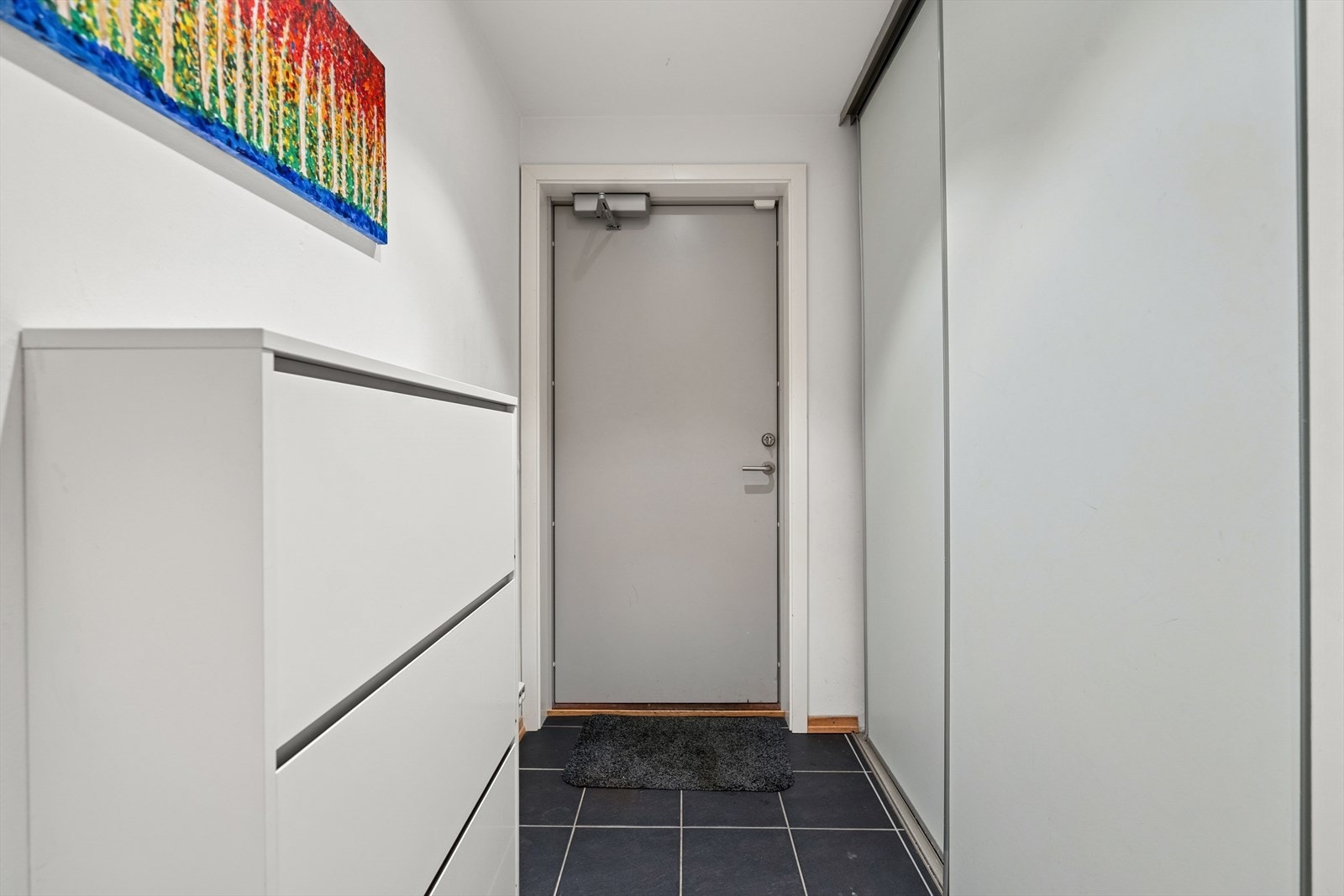 Du ønskes velkommen inn i en hyggelig flislagt entrè utstyrt med skyvedørsgarderobe Galleribilde