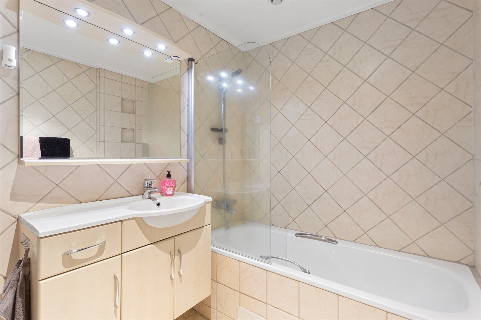 Bad i u. etasje med innfliset badekar og vegghengt dusj Galleribilde