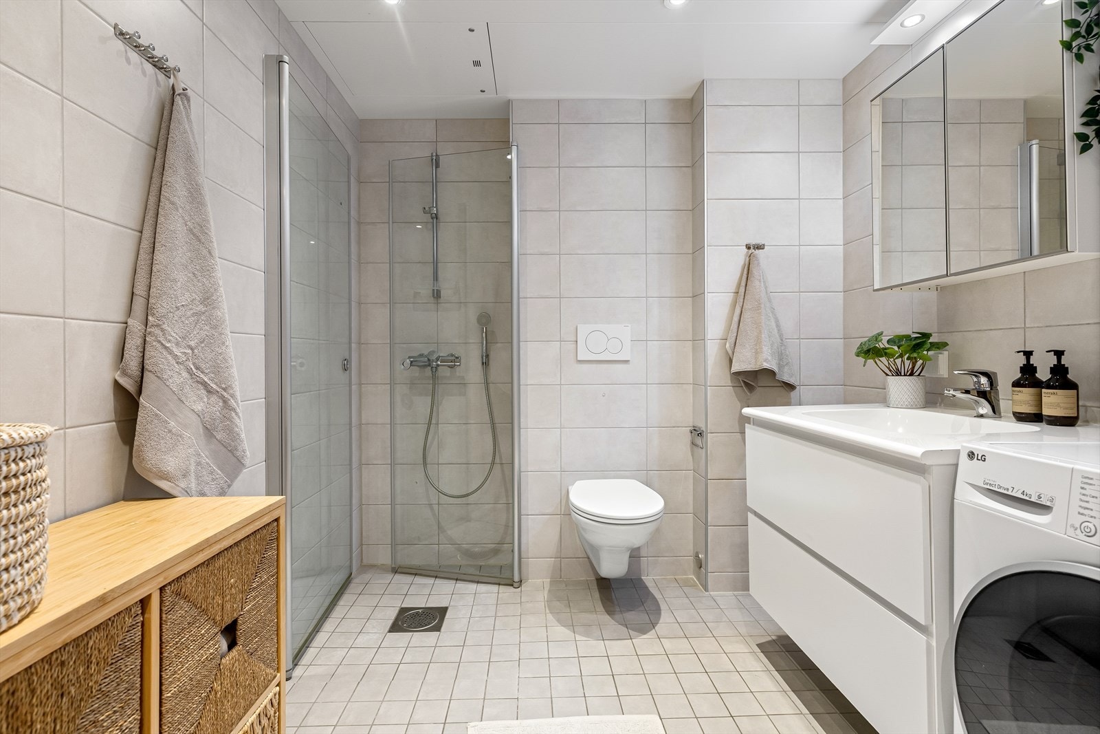 Lekkert bad med lekre lyse flis på vegger og gulv. Dusjhjørne med innfellbare dører og godt med oppbevaringsplass. Galleribilde