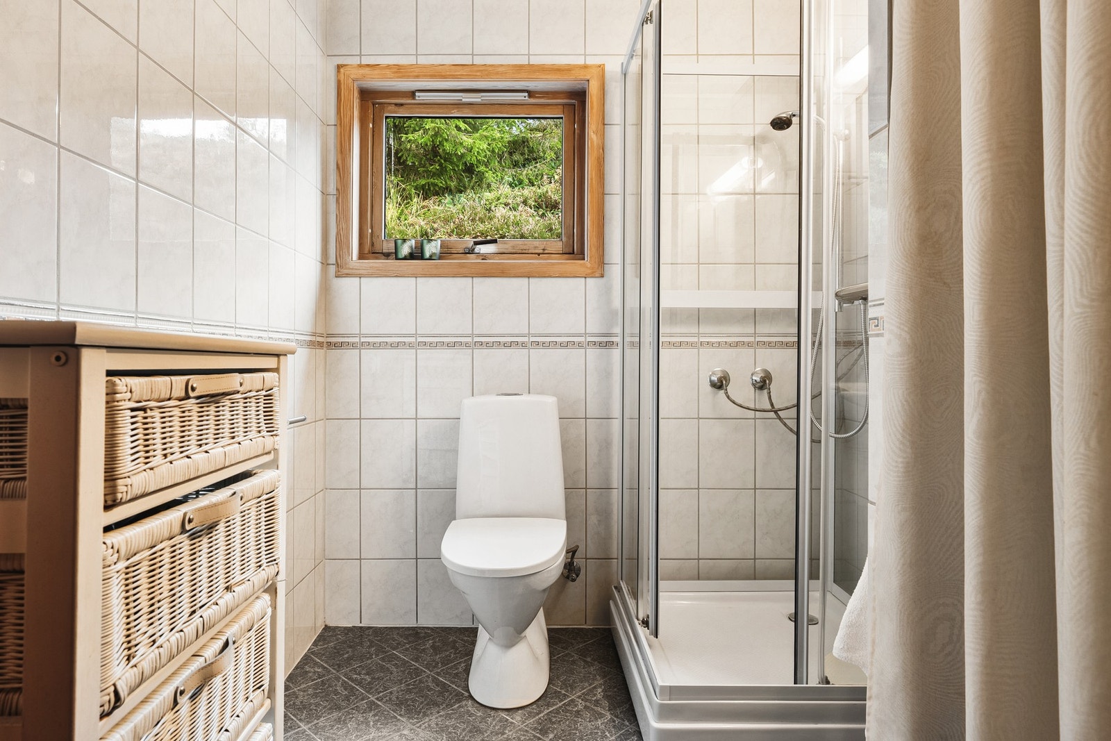 Det ene badet er innredet med dusjkabinett, servant og toalett, samt fliser på både gulv og vegger. Galleribilde