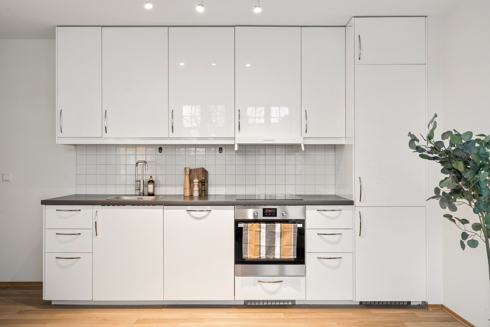 Pent kjøkken fra 2014 med hvite fronter og mørk benkeplate. Galleribilde