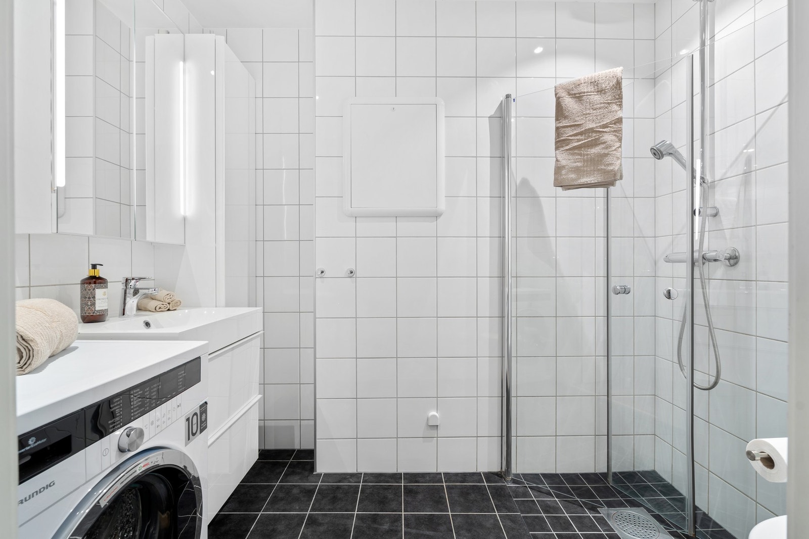 Pent baderom fra 2014 med dusjhjørne, servantinnredning og opplegg for vaskemaskin. Galleribilde