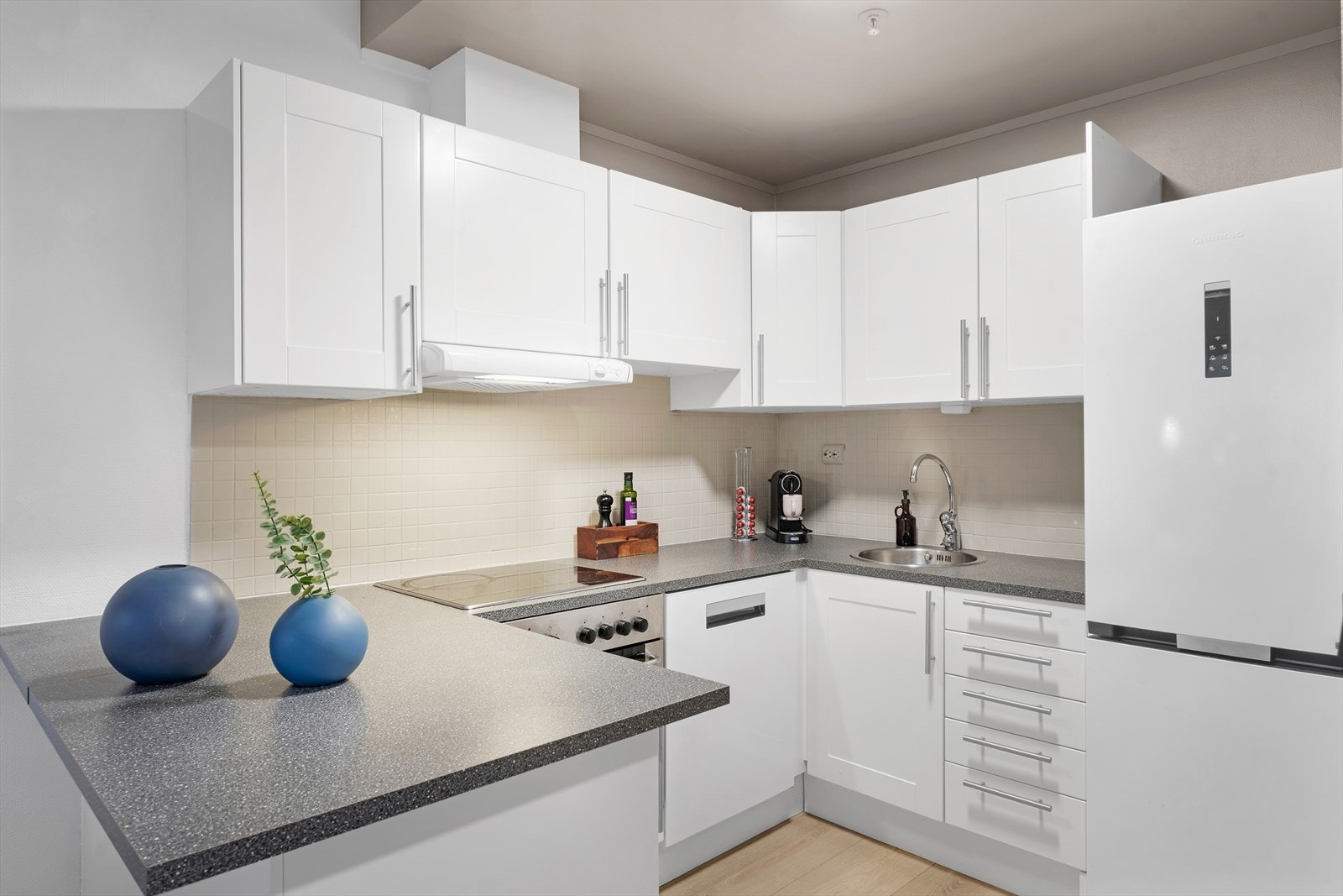 Flott kjøkken i hvit utførelse med profilerte fronter og delvis integrerte hvitevarer. Galleribilde