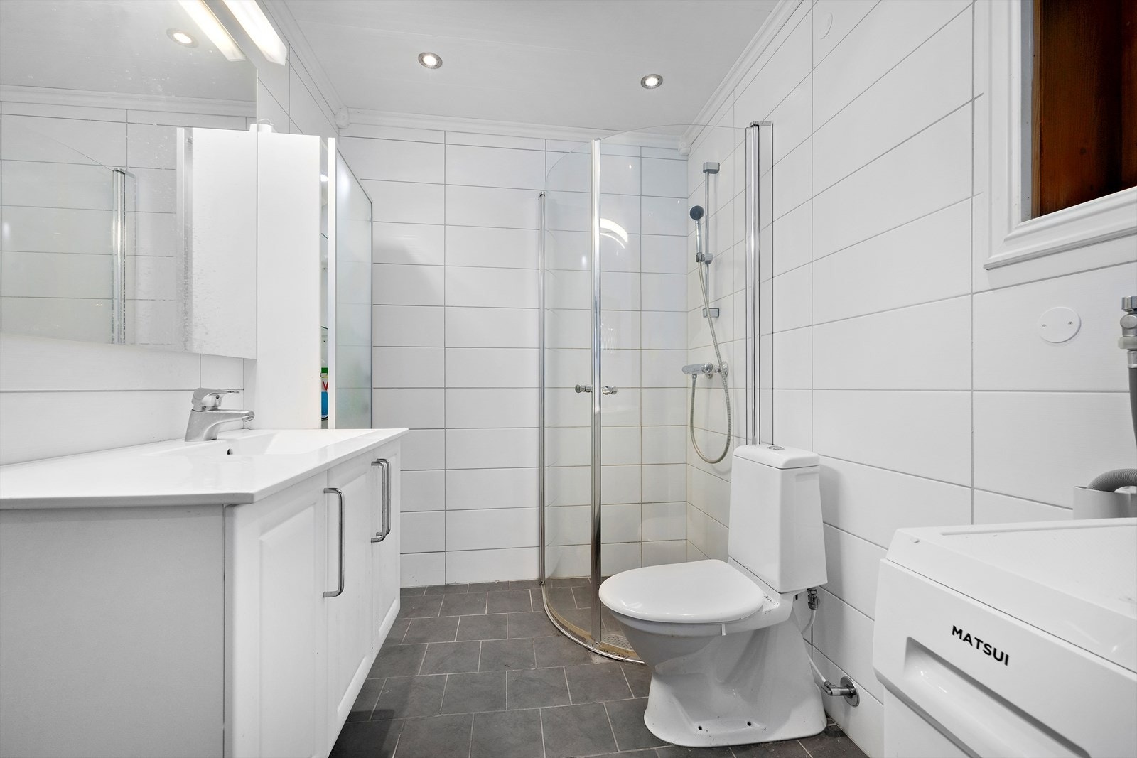 Bad/vaskerom ble oppgradert i 2012 og er innredet med toalett, dusjdører, innredning med servant og opplegg for vaskemaskin. Her er det flislagt gulv med varmekabler, flislagte vegger og takplater med spotter. Galleribilde