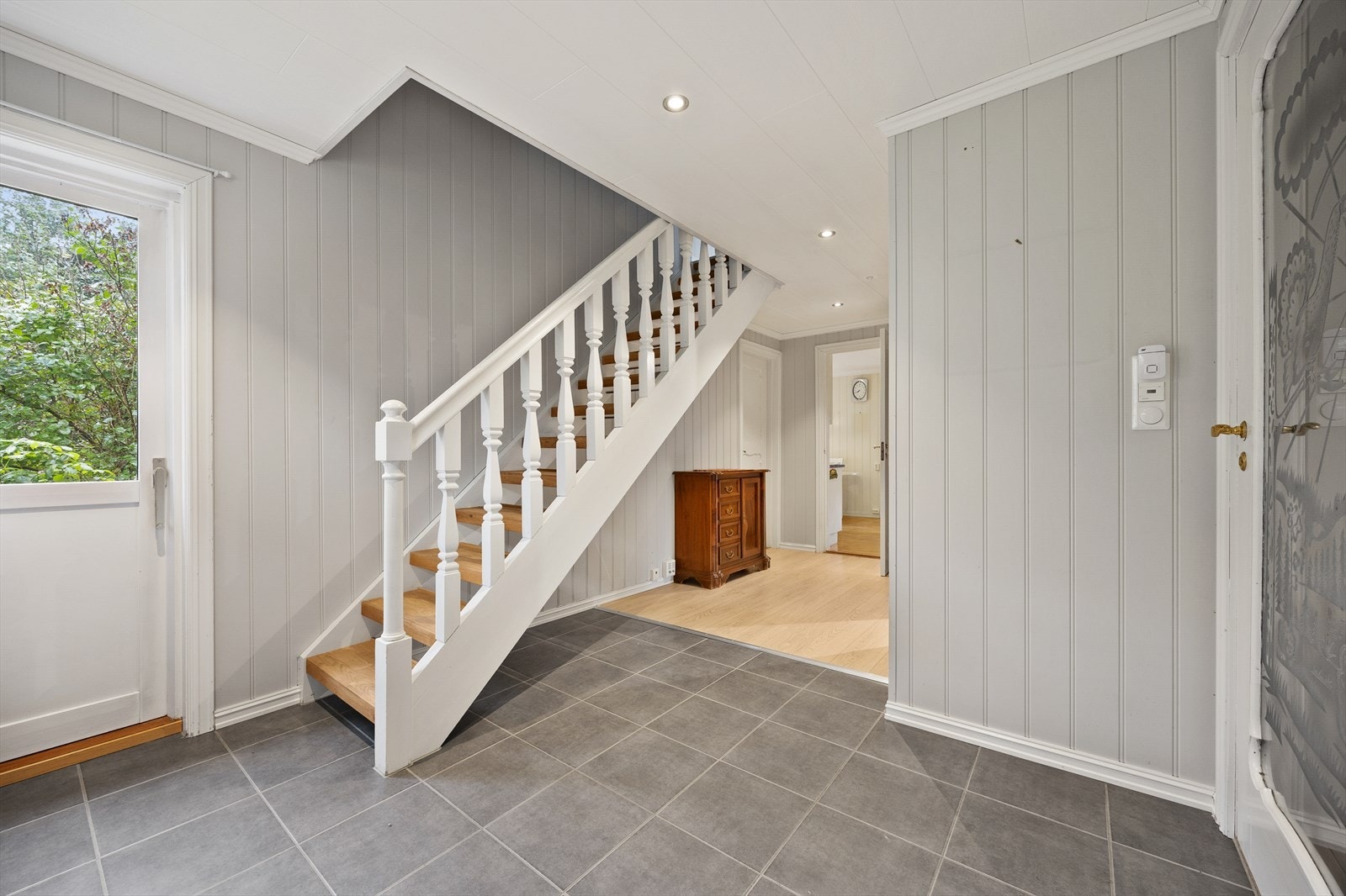 Videre inn er det en romslig hall med utgang til baksiden av boligen og trapp opp til loftetasjen. Galleribilde