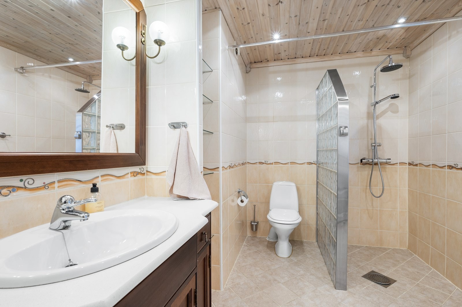 Badet er flislagt og inneholder servant i innredning, wc, dusj og opplegg til vaskemaskin. Galleribilde