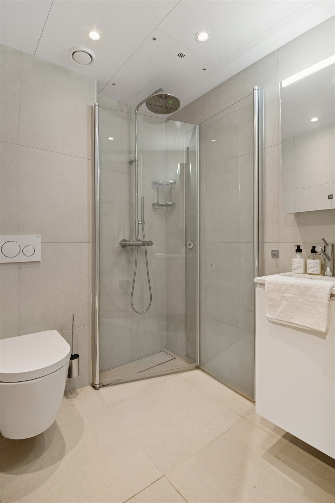 Rommet er innredet med vegghengt wc, dusjhjørnet med innfellbarer dører, regnfall- og hånddusj, servant med underskap, speilskap med belysning. Galleribilde