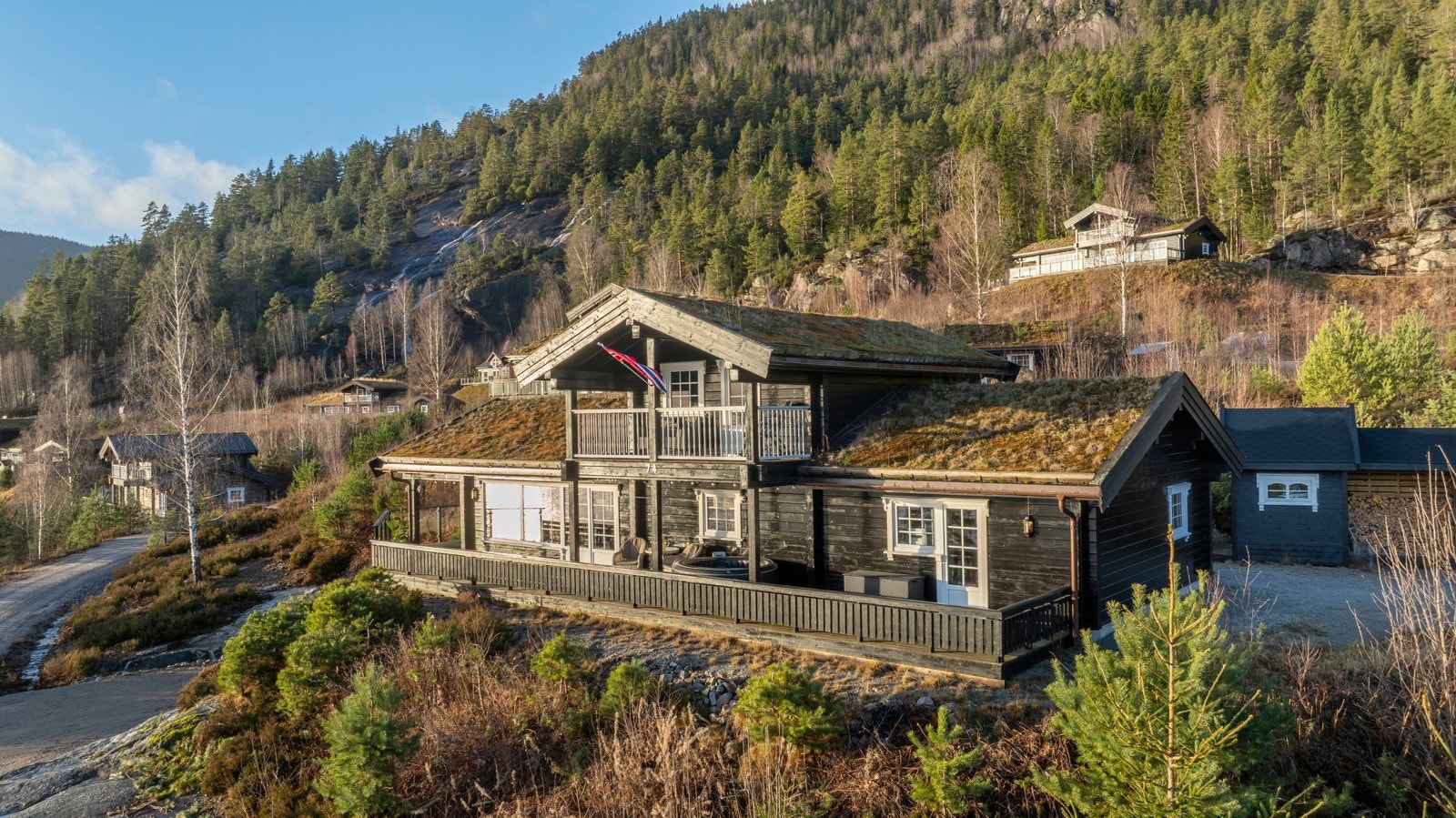 Oversiktsbilde av hytta med flott beliggenhet i skrånende terreng. Galleribilde