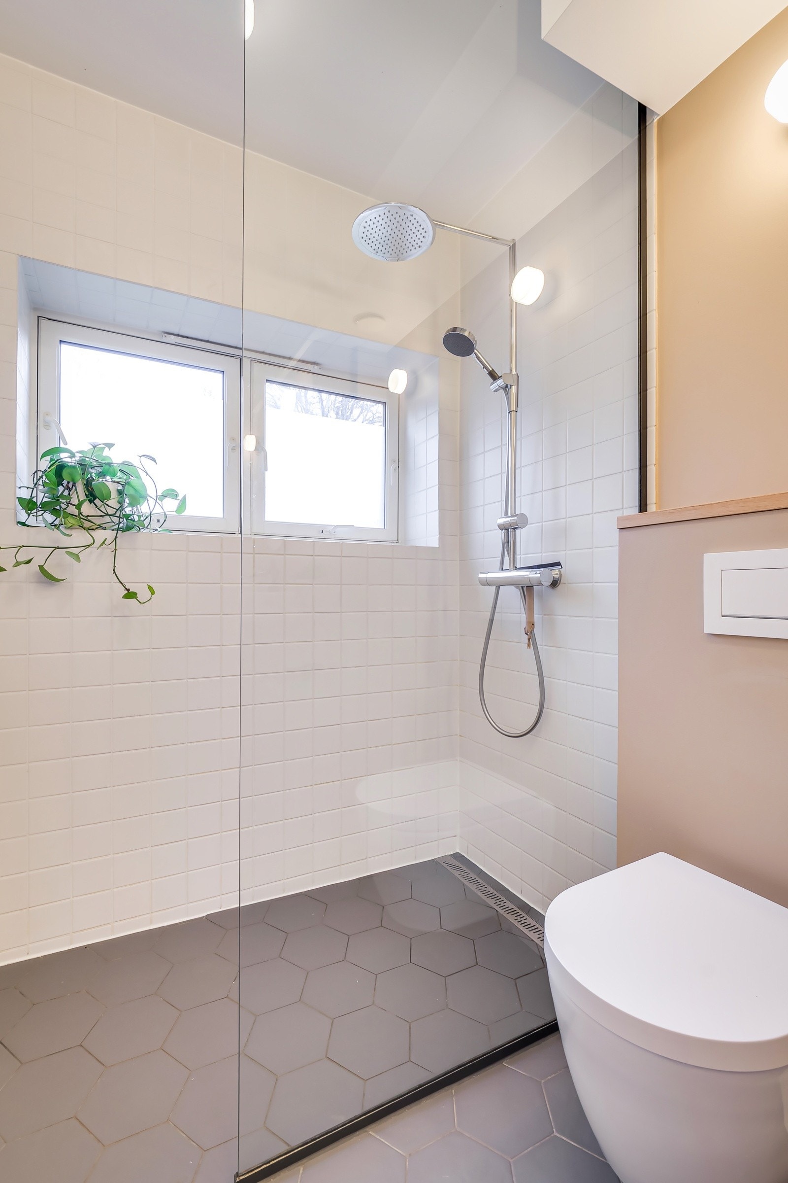 Innbydende og delikat, med fliser på vegger og gulv. Innredning med romslig dusjsone med regnfallsdusj og glassvegg som skjermer. Galleribilde