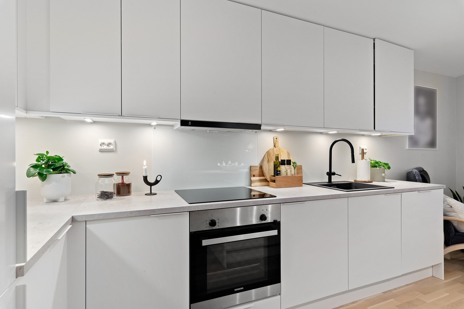 Glassplate montert mellom kjøkkenbenk og overskap bak platetopp Galleribilde