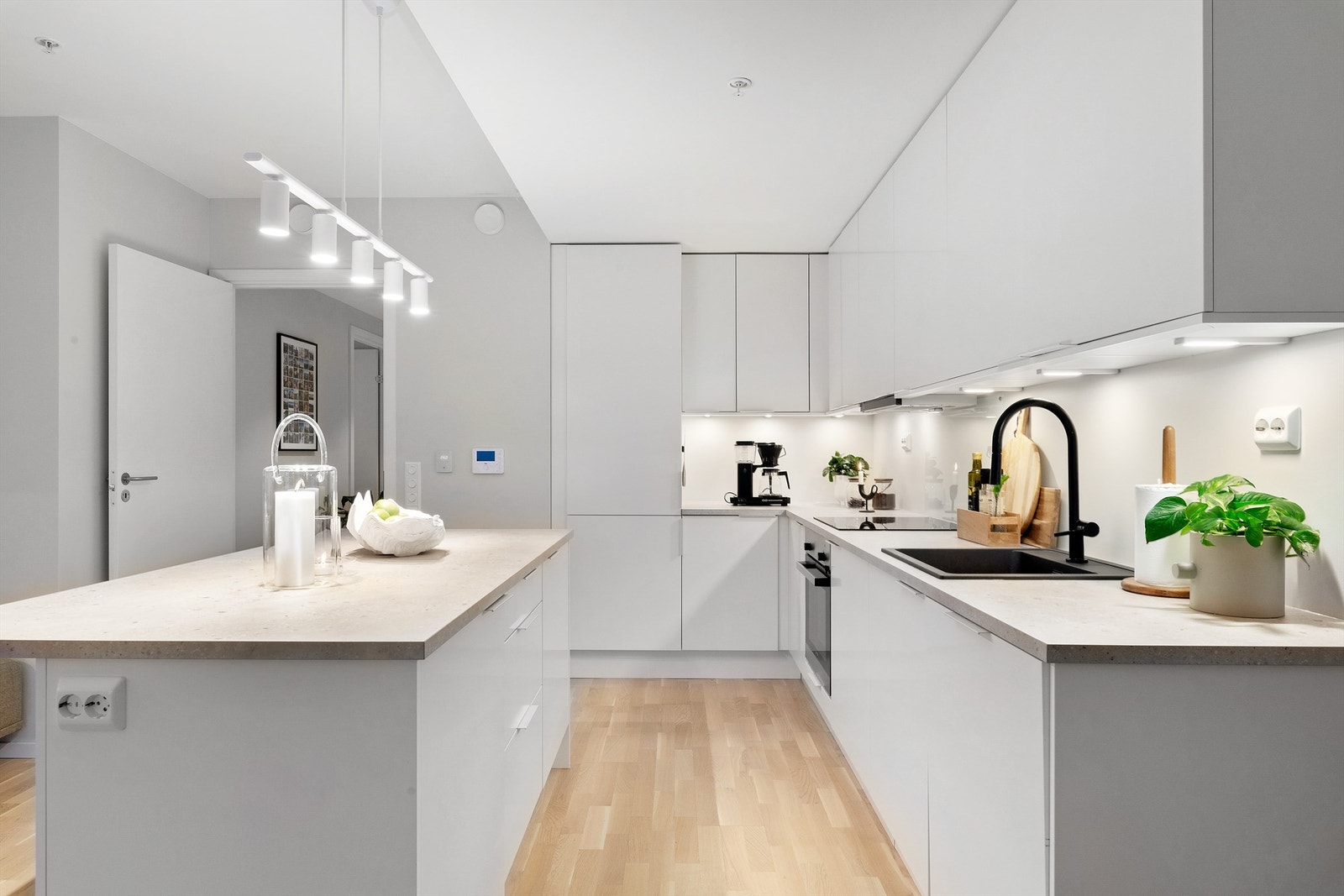 Nedfelt oppvaskkum med ett-greps kjøkkenarmatur. Ventilator i overskap med komfyrvakt. Automatisk vannstopper med fuktsensor synlig under oppvaskkum. Galleribilde