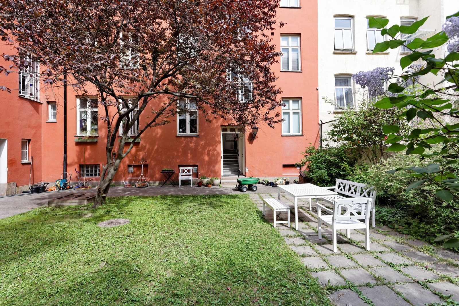 Bakgården er pent opparbeidet med gressplen, beplantning, trær og sittegrupper Galleribilde