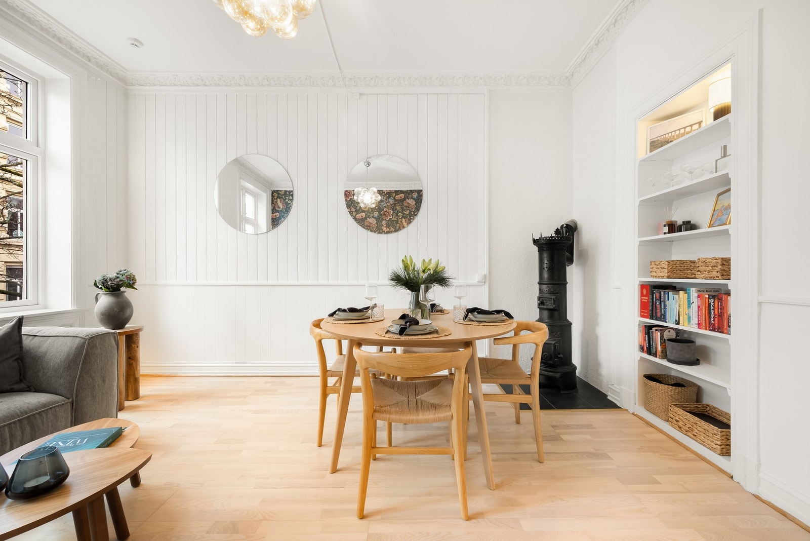 Romslig stue med naturlig soner til sofagruppe med tilhørende møblement, spisebord, innfelt dekorhylle og flott støpejernsovn Galleribilde