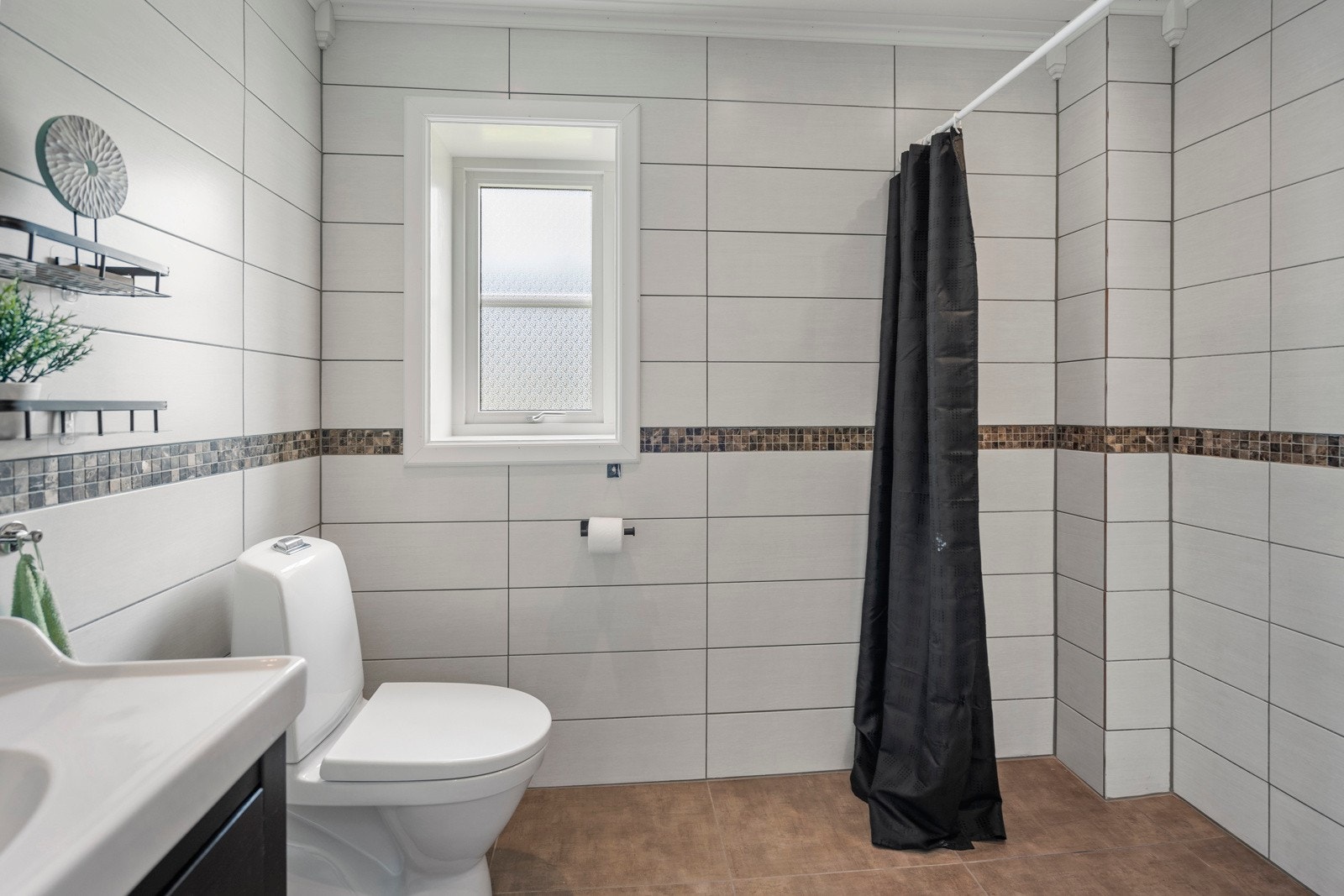 Badet er utstyrt med toalett, servantinnredning og dusjhjørne. Galleribilde