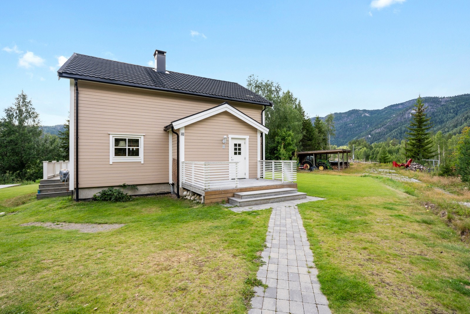 Tomten er pent opparbeidet med plen, belegningsstein, og noe beplanting. Galleribilde