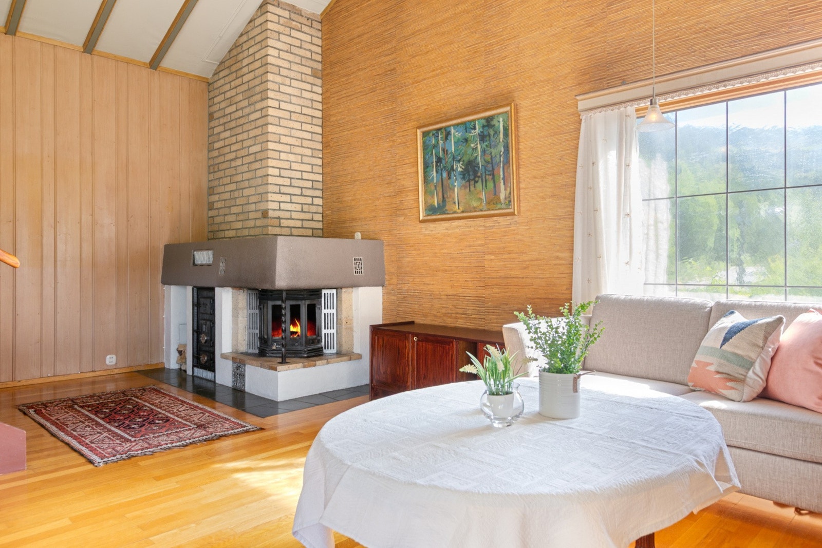 Den plassmurte peisen med innsats bidrar til ekstra varme i den kalde årstida. Parafinovn ved siden av peisen. Galleribilde