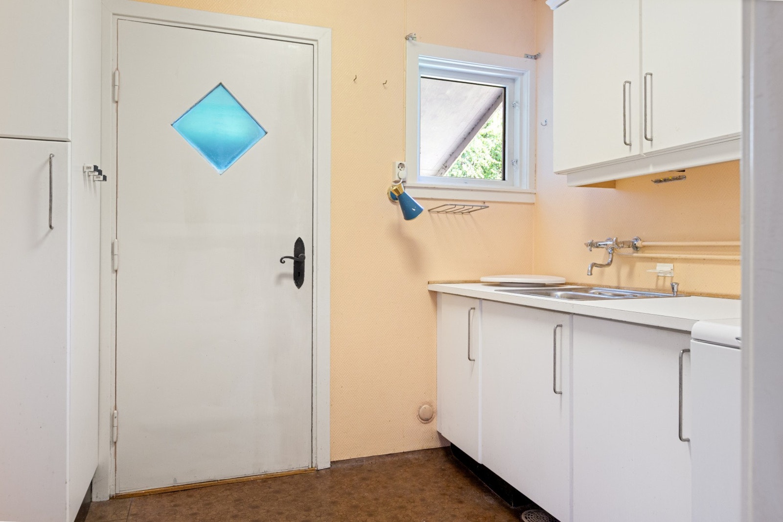 Vaskerom med opplegg for vaskemaskin og montert servant med over- og underskap, samt plassbygd tørkeskap. Utgang til oversiden av huset. Galleribilde