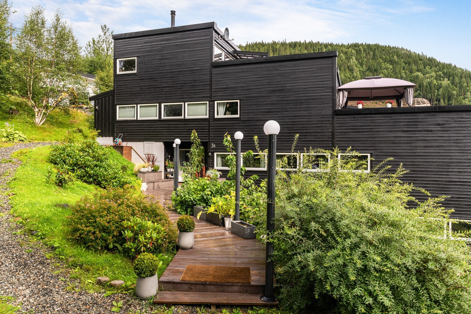 Leiligheten har et tiltalende inngangsparti opparbeidet av selger i 2024, med beplantning og installert vannslange. Galleribilde