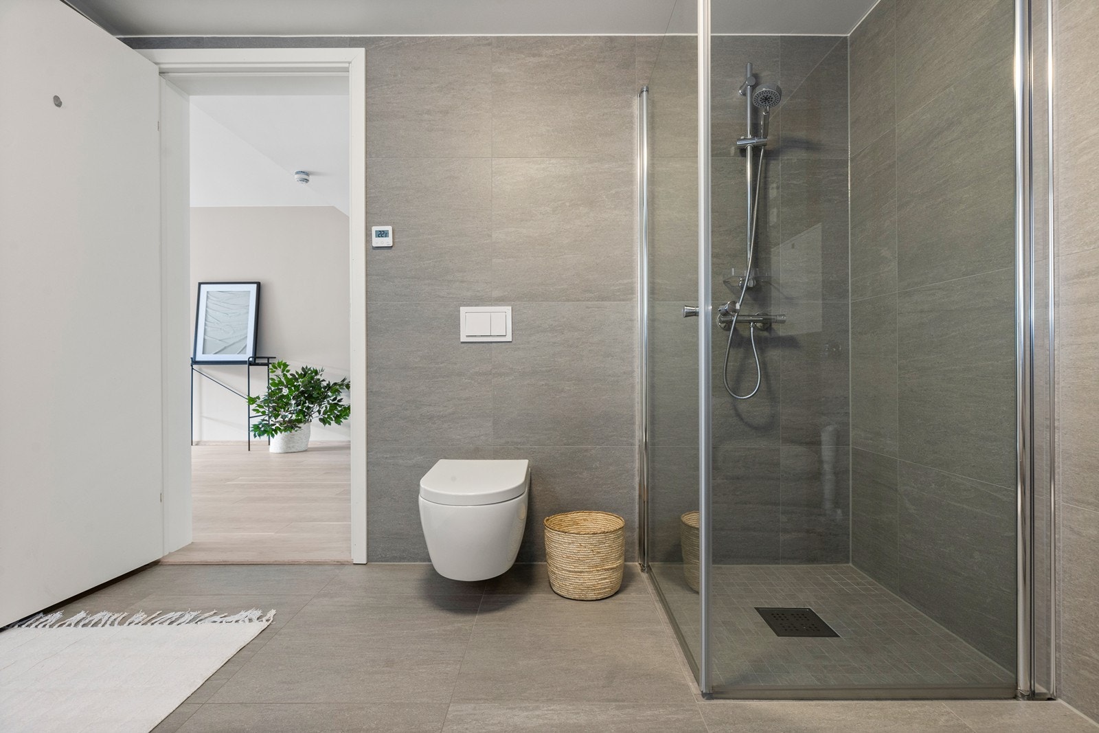 Delikat, helfliset baderom i tidløse farger og stilren innredning med heldekkende servant og slette fronter på skuffene, samt speil med lys. Det er opplegg for- og god plass til vaskemaskin. Galleribilde