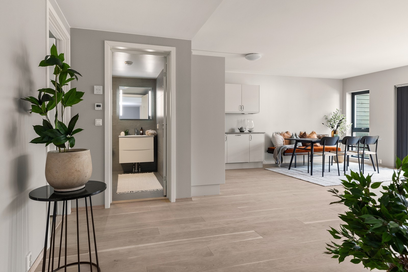 Romslig stue med flere store vindusflater, som slipper inn mye dagslys og gir en luftig følelse. Stilrene overflater i nøytrale farger og en-stavs hvitpigmentert eikeparkett på gulvet. Galleribilde