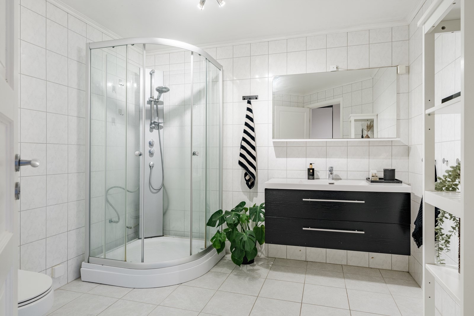 Badet er innredet med dusjkabinett, gulvmontert toalett og servantskap. Galleribilde