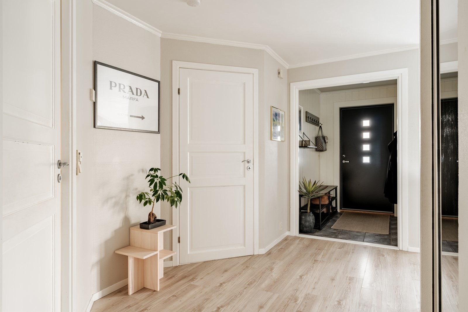 Lys og innbydende entré med flislagt gulv, malt panel på veggene og malt himling. Rommet byr på praktiske løsninger for oppbevaring og god plass til å henge fra seg yttertøy og sko. Galleribilde