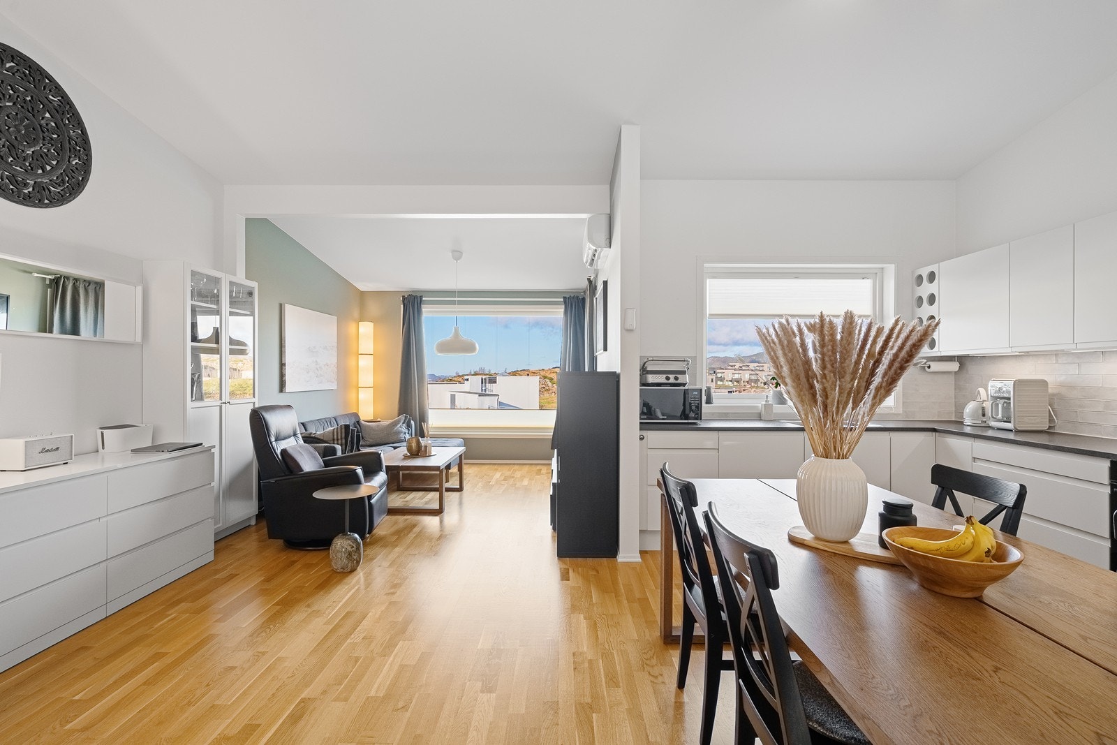 Den åpne løsningen mellom kjøkken og stue gir rikelig plass til et stort spisebord, ideelt for hyggelige middager og samlinger. Galleribilde