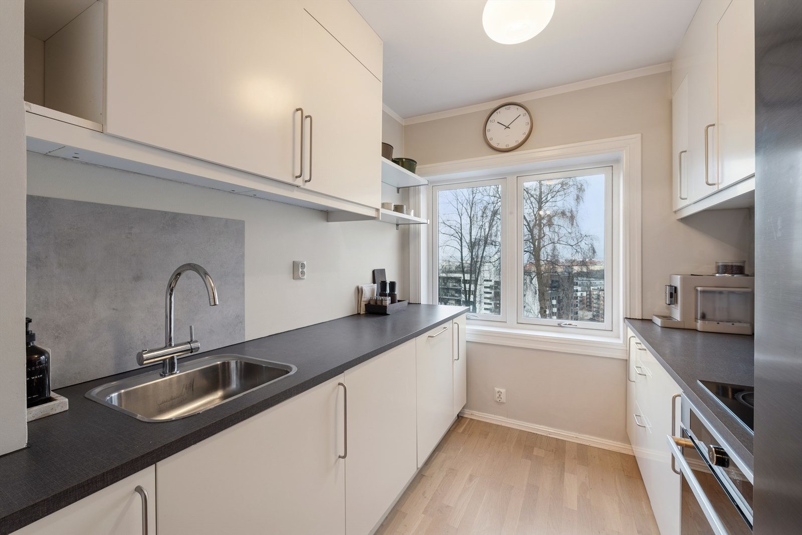 Kjøkkeninnredning med glatte, fabrikklakkerte fronter. Laminat benkeplate med nedfelt kum i rustfritt stål. Galleribilde