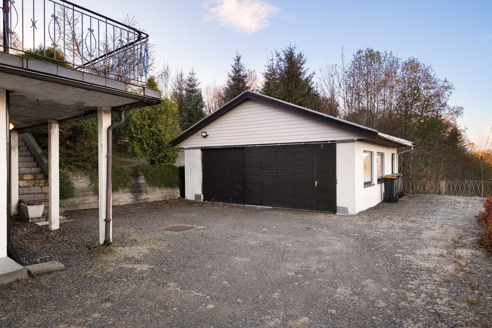 Garasjen har et saltak med w-takstoler og er bygget med lecablokker. Det er strøm til garasjen, og den har en skyvedør med liggende kledning Galleribilde