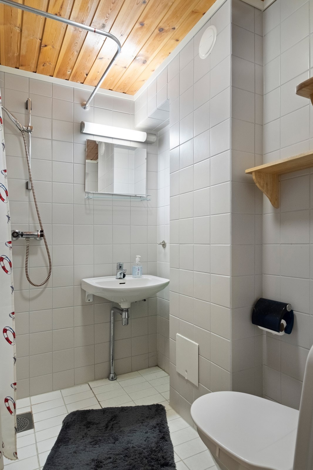 Bad med flislagte vegger og gulv med dusj og toalett Galleribilde