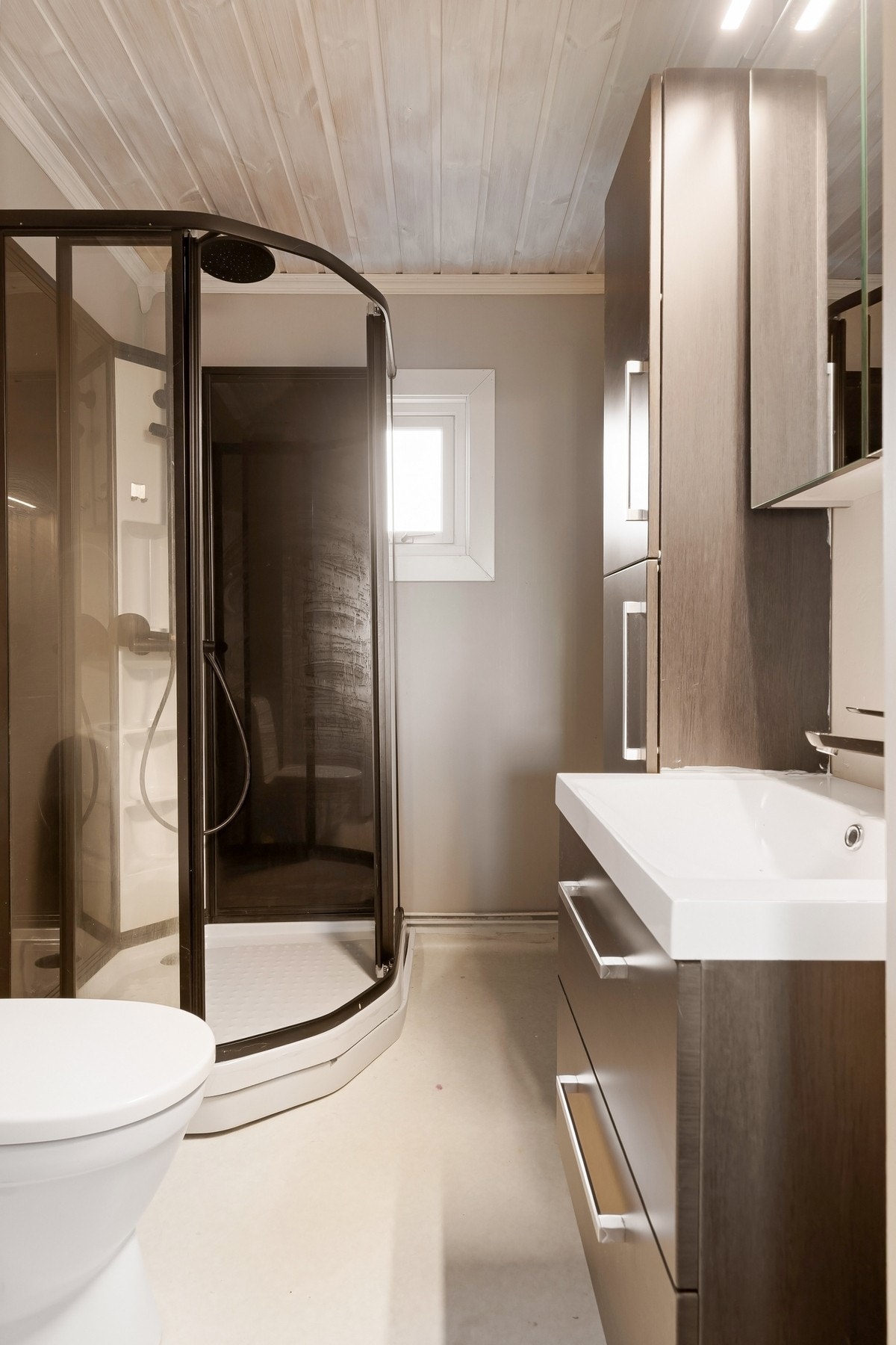 Bad med dusjkabinett, toalett og romslig innredning/høyskap til lagring av baderomsartikler. Galleribilde