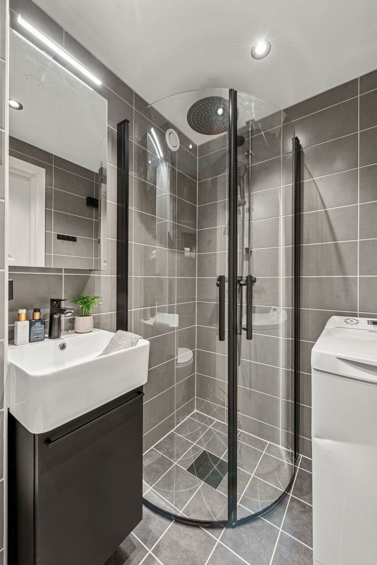 Dusjsonen er innredet med moderne, sorte detaljer og har praktiske, vendbare dører i herdet glass, samt regnfalldusj og hånddusj. Vaskemaskin følger med. Galleribilde