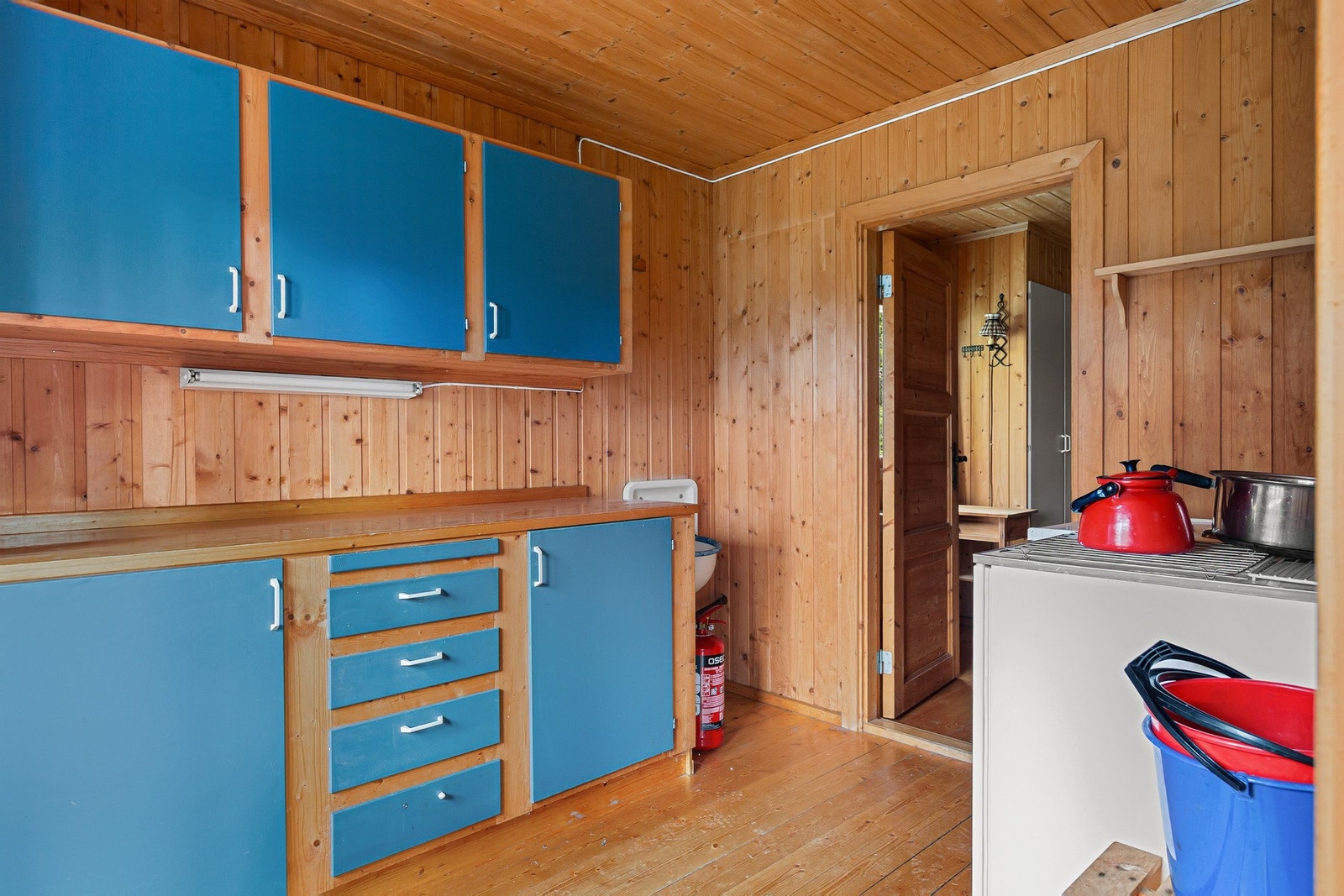 Plassbygd og enkel kjøkkeninnredning i heltre, med glatte fronter. Galleribilde